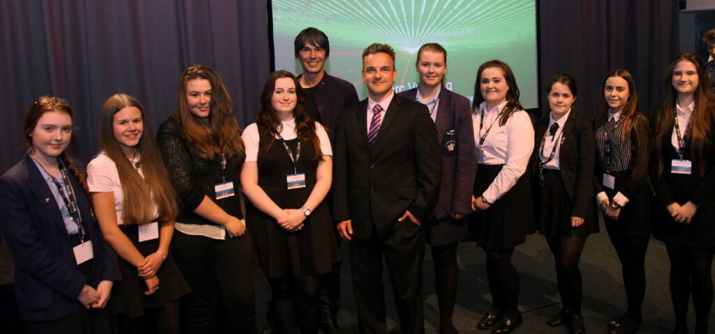 Prof. Brian Cox and Prof. Carsten Welsch with students at the Symposium.
