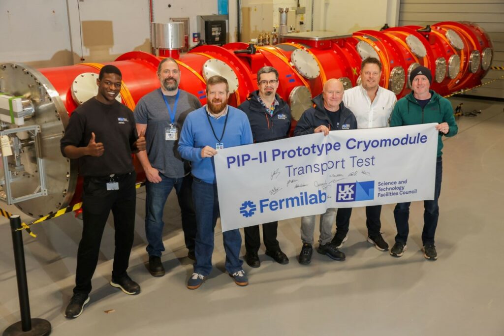 A group of people holding a banner in front of a machine.