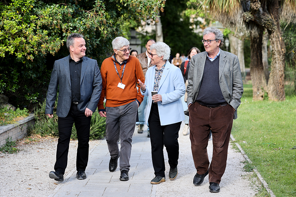 A group of people smiling and walking along a path in a park.