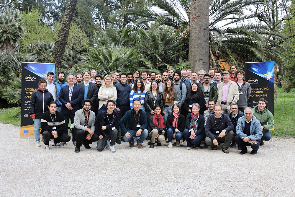 A group of people posing for a photo in fron of palm trees.