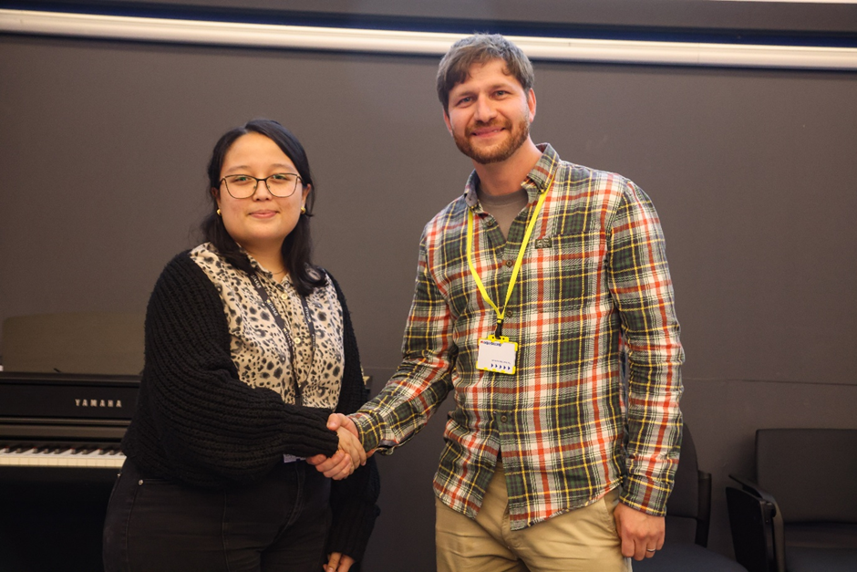 To people shaking hands and looking into the camera.