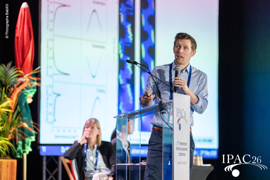 A person presenting a talk. Standing next to lectern. Pointing with laser pointer.