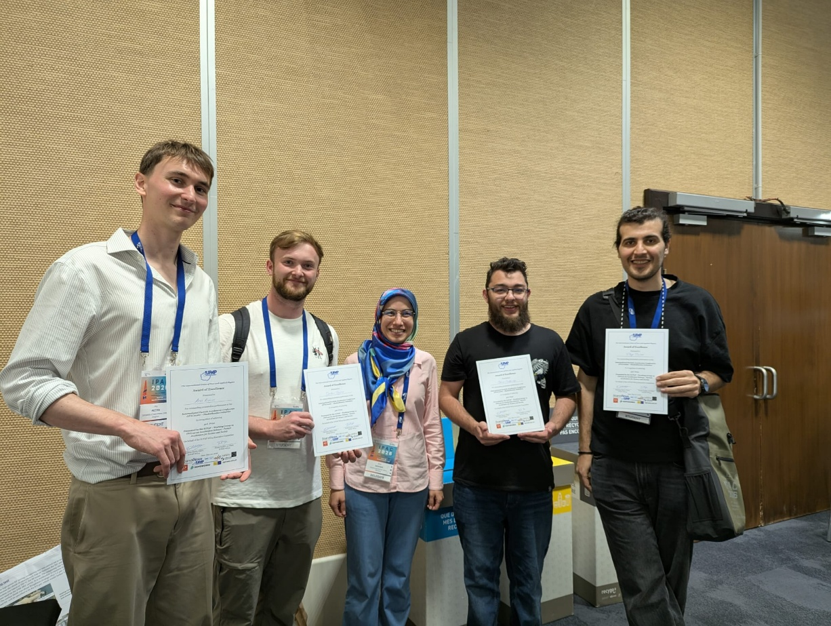 Five people posing for a picture. Four of them are holding certificates in their hands.