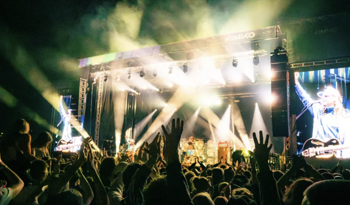 People dancing in front of a large stage at a festival.